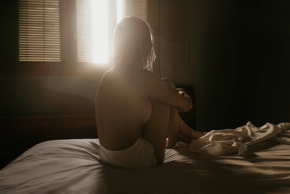 Woman sitting in quiet meditation by a window, focusing on nervous system regulation through breath